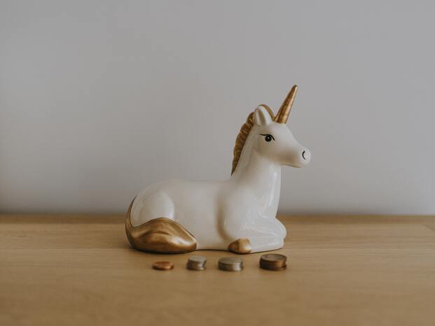 A unicorn toy in front of small stack of coins